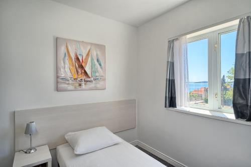 a bedroom with a bed and a window with a sailboat at Hotel Aqua - Guest Rooms & Suites Kaštela in Kaštela