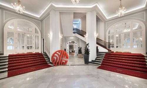 a lobby with red stairs and a red chair at NH Collection Gran Hotel de Zaragoza in Zaragoza