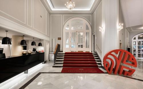 una escalera con una silla roja y una alfombra roja en NH Collection Gran Hotel de Zaragoza, en Zaragoza