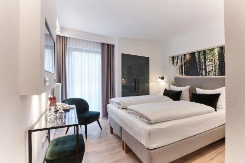 ein weißes Schlafzimmer mit einem Bett, einem Tisch und einem Stuhl in der Unterkunft Berghotel Lothar-Mai-Haus in Hofbieber