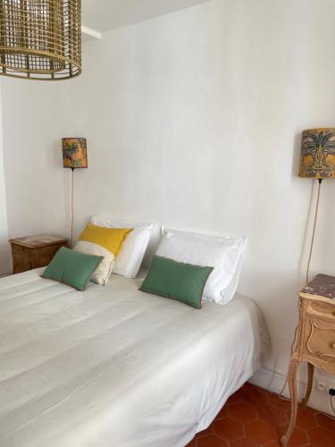 a white bed with two green pillows on it at Maison Lligat, appartements dans le centre historique in Perpignan