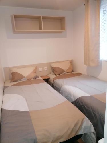 deux lits assis dans une pièce avec une fenêtre dans l'établissement Mar lestang mobilhome 3chambres, à Canet