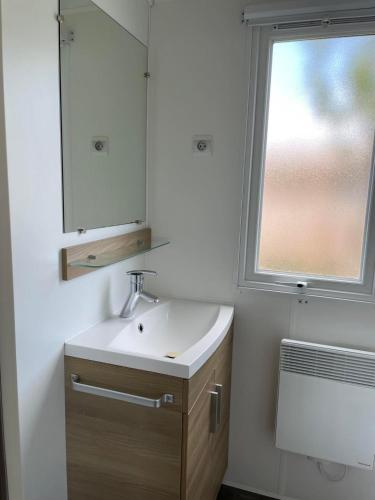 une salle de bain avec un lavabo, un miroir et une fenêtre dans l'établissement Mobil Home tout confort 6 personnes avec wifi, à Onzain