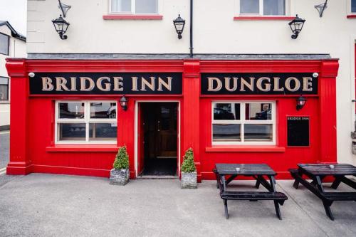 a red building with two benches in front of it at Bridge Inn Studio Apartments in Donegal