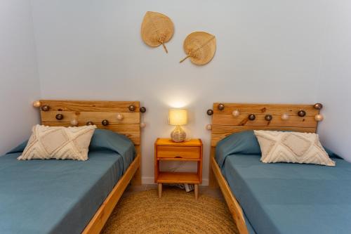 two twin beds in a room with a night stand at Denia Apartment Marina Real in Denia