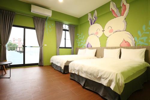 two beds in a room with two rabbits painted on the wall at 蘑菇奇緣民宿 in Taitung City