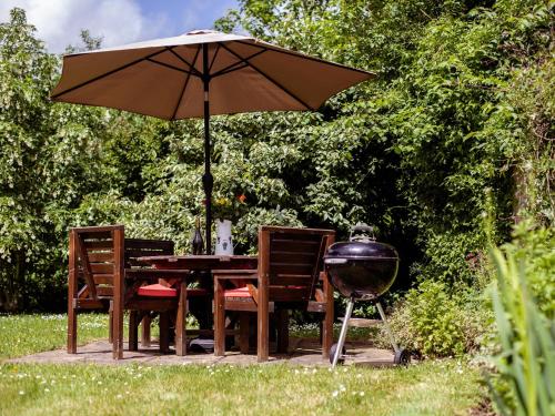 mesa y sillas con sombrilla y parrilla en Amber Cottage en Little Witcombe