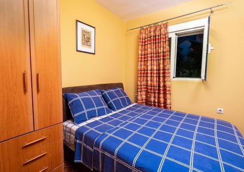 um quarto com uma cama azul e uma janela em APARTMANI VUKADINOVIC LUX em Budva