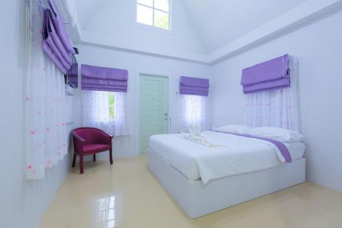 a bedroom with a white bed and a red chair at บ้านสวนทิวภูผาวัดเจดีย์ไอ้ไข่ in Ban Sai Liang