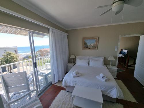 a bedroom with a white bed and a balcony at The Bay Lodge in Gansbaai