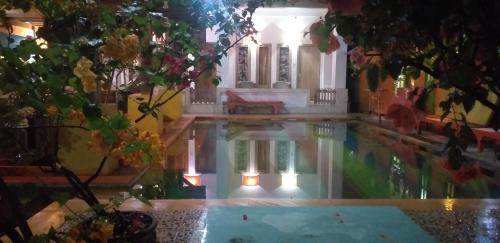ein Pool in einem Haus mit Bäumen und einem Gebäude in der Unterkunft Alola inn in Padangbai