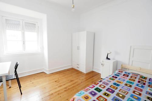 a white bedroom with a bed and a desk at Olaias13 in Lisbon