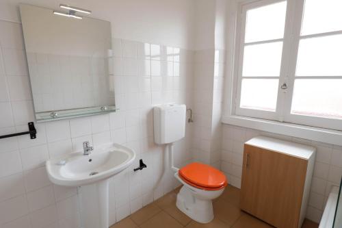 een badkamer met een toilet en een oranje stoel bij Olaias13 in Lissabon