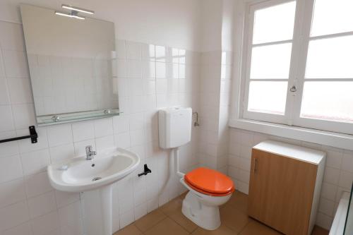 a bathroom with a toilet with an orange seat at Olaias13 in Lisbon