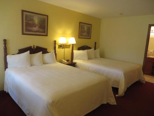 two beds in a hotel room with white sheets at Honeysuckle Inn in Mountain View