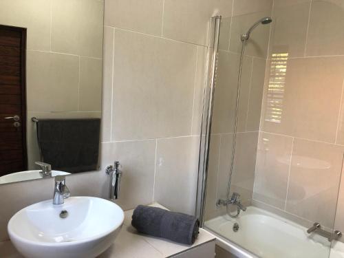 a white bathroom with a sink and a shower at Fiori Rosa in Bloemfontein