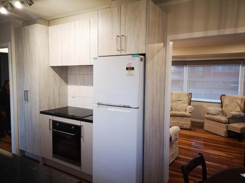 a kitchen with a white refrigerator in a room at Cheerful 4 Bedroom Holiday Home (Sleeps 7) in Rotorua