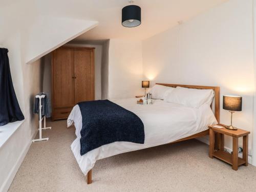 1 dormitorio con 1 cama blanca grande y 2 lámparas en Lavender Cottage, en Okehampton