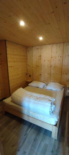 une chambre avec un lit dans une cabane en bois dans l'établissement Cahute de montagne pour profiter du Haut Jura, à Prémanon