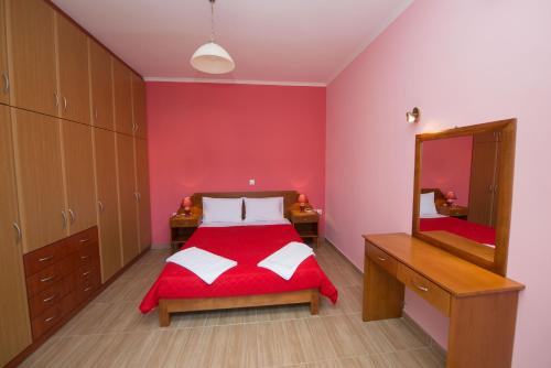 a red bedroom with a bed and a mirror at Anna Apartments in Acharavi