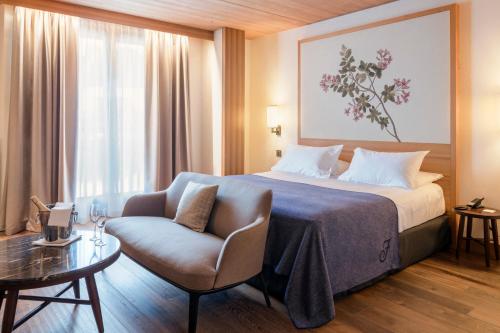 a hotel room with a bed and a chair at Faloria Mountain Spa Resort in Cortina dʼAmpezzo