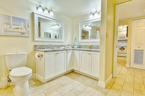 a bathroom with a toilet and a sink and two windows at Beach Cottage 2402 in Clearwater Beach