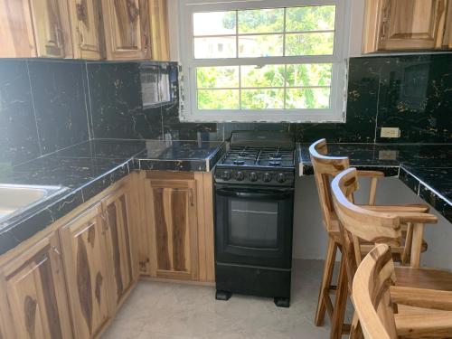 a kitchen with wooden cabinets and a stove and a window at Robin Hood Guest House in Port Antonio