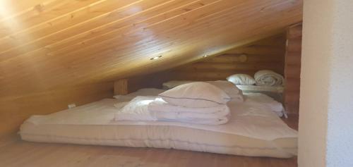 a bed with white blankets and pillows in a room at Järvenrantamökki Himoksella poreammeella in Jämsä