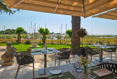 a patio with tables and chairs under a wooden umbrella at Palazzo Rainis Hotel & Spa - Small Luxury Hotel - Adults Only in Novigrad Istria