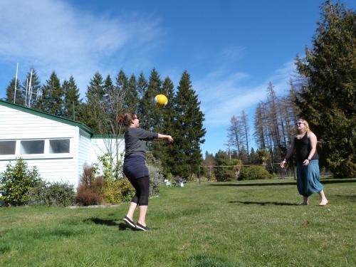 two women playing with a ball in a yard at Alpine Holiday Apartments & Campground in Hanmer Springs