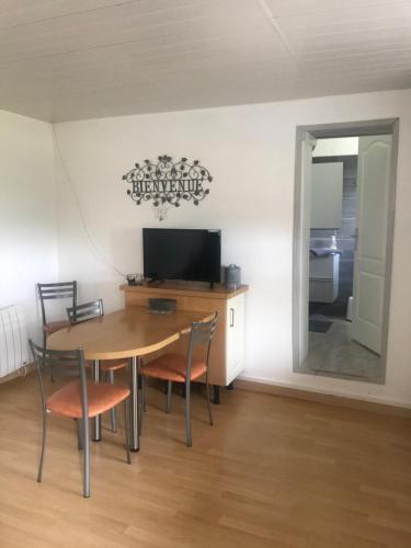 a dining room with a table and chairs and a television at Le Havre de Samara in Nurlu