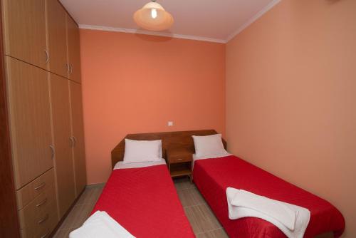 two beds in a small room with orange walls at Anna Apartments in Acharavi