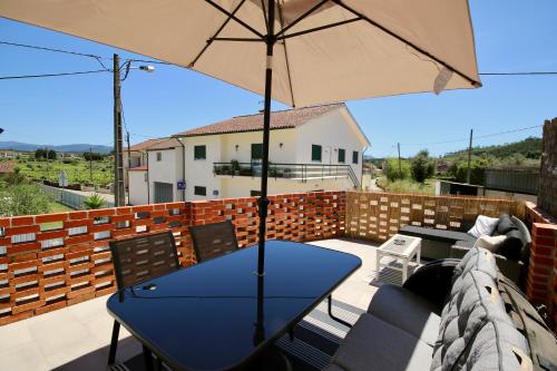 a patio with a blue table and an umbrella at Casa Nórdica in Chão de Lamas
