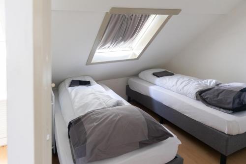 two beds in a room with a window at Museumhuisje 013 in Tilburg