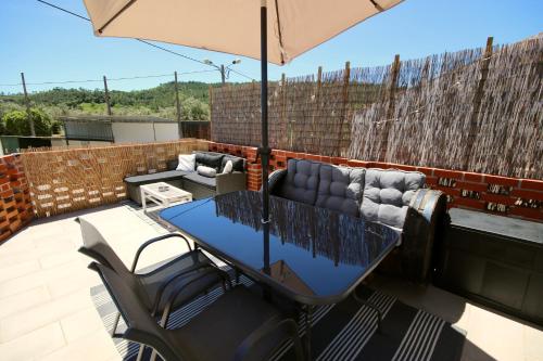 a table and chairs on a patio with an umbrella at Casa Nórdica in Chão de Lamas