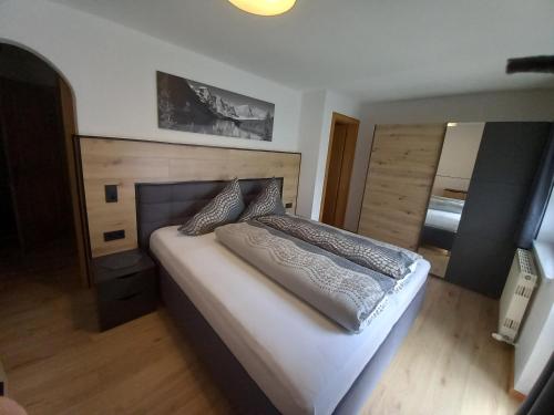 Schlafzimmer mit einem großen Bett mit einem Kopfteil aus Holz in der Unterkunft Haus Waldfriede in Sankt Leonhard im Pitztal