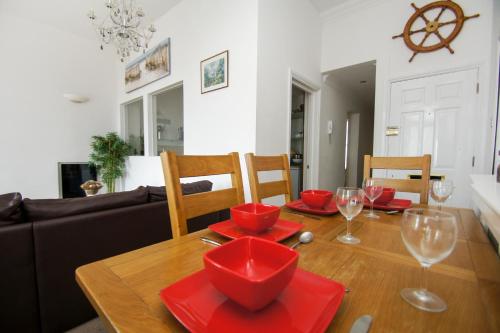 ein Esszimmer mit einem Tisch mit roten Platten und Weingläsern in der Unterkunft Marine Parade Sea View - by Brighton Holiday Lets in Brighton & Hove