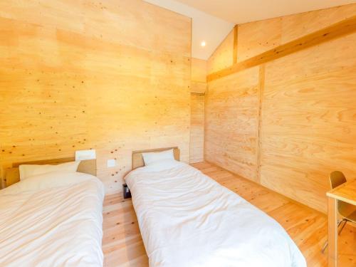 two beds in a room with wooden walls at Guest House Amami Long Beach 2 - Vacation STAY 36312v in Amami