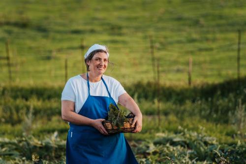 eine Frau, die auf einem Feld steht und einen Korb von Pflanzen hält in der Unterkunft Terre Di Himera in Buonfornello