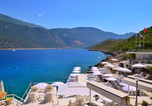 a group of chairs and umbrellas next to a body of water at Club Çapa Hotel in Kas