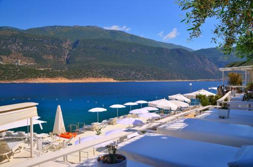 a beach with umbrellas and chairs and the water at Club Çapa Hotel in Kas