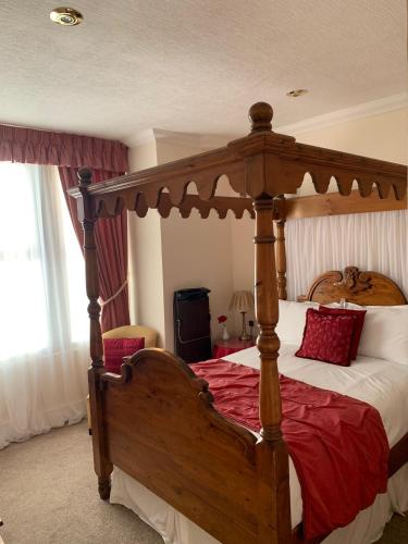 a bedroom with a wooden canopy bed with red sheets at The Old Coach House in Blackpool