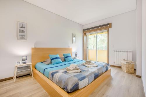 Furadouro Beach and Club Apartment في أوفار: غرفة نوم بسرير كبير مع وسائد زرقاء