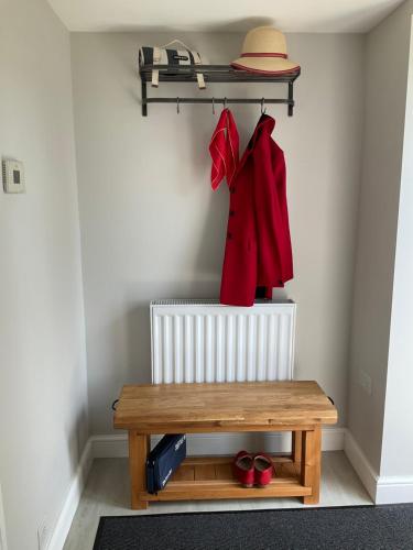a room with a bench and a red coat and a hat at Hillside Haven, panoramic views Nr Bakewell in Great Rowsley