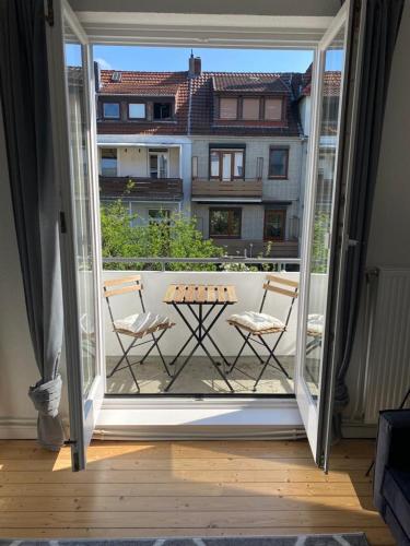 uma porta aberta para uma varanda com uma mesa e cadeiras em Schönes 2-Zimmer-Apartment in Bremen, Findorff em Bremen