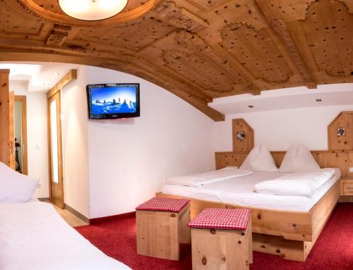 two beds in a room with a tv on the wall at Haus Tanja in Sölden