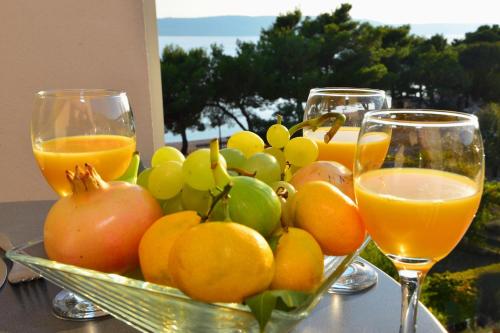 a bowl of fruit and two glasses of orange juice at Villa Dalmatina in Živogošće
