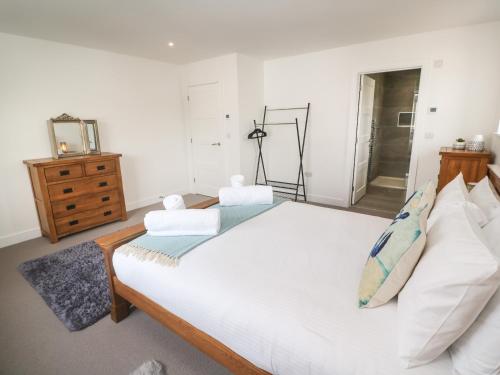a bedroom with a large white bed and a dresser at 3 Praa Cove in Penzance