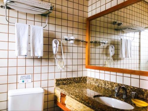 uma casa de banho com um lavatório, um espelho e um WC. em Ilha Flat Hotel Suíte Bella - 4207 - Ilhabela em Ilhabela