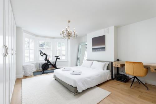 een witte slaapkamer met een bed en een bureau bij Spacious 2 bedroom apartment with beautiful garden in Brighton & Hove